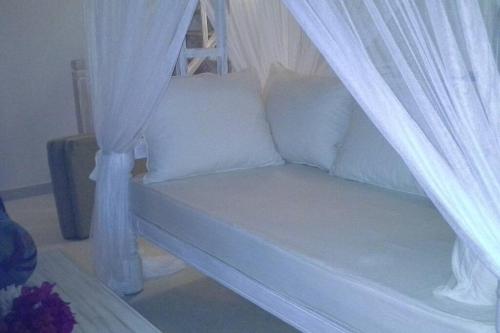 biała kanapa z zasłonami w pokoju w obiekcie Swordfish Villas Samaki House (n.4) w mieście Malindi