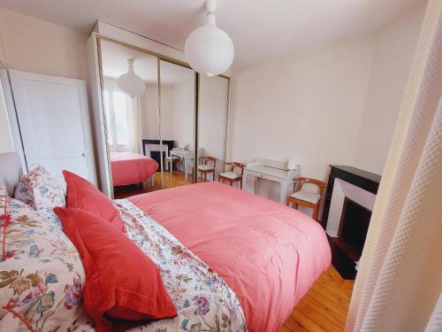 a bedroom with a pink bed with red pillows at Villa Capucine - Maison de ville avec jardin dans Vernon-Giverny, proche des transports et de la gare in Vernon