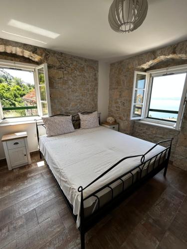 a bedroom with a bed in a room with two windows at Stone house Kurtić stara Podgora in Podgora