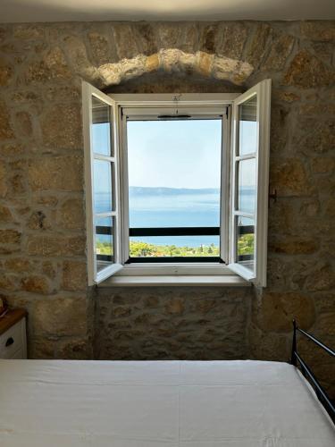 a bedroom with a window with a view of the ocean at Stone house Kurtić stara Podgora in Podgora