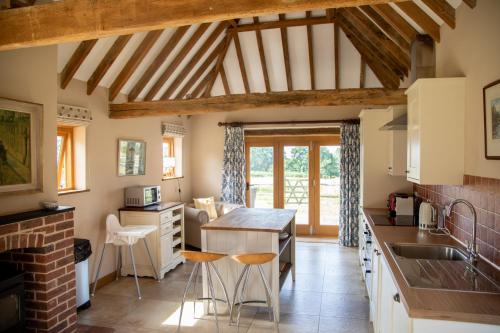 uma cozinha com tectos em madeira, uma mesa e bancos em The Cowshed em Hooe