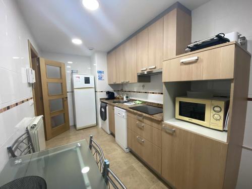 a kitchen with wooden cabinets and a microwave at APARTAMENTO El Roxu 2 in Arriondas