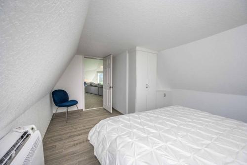 a white bedroom with a bed and a blue chair at Sumner Lake Tiny House in Clermont