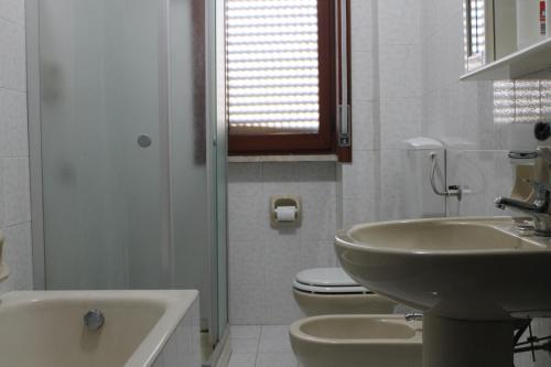 bagno bianco con lavandino e servizi igienici di Lago delle Magnolie Baia Verde a Gallipoli