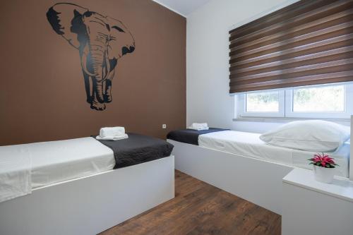 two beds in a bedroom with a picture of a elephant on the wall at Ivano in Ston