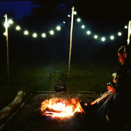 a person sitting around a fire at night at La Prairie Étoilée Luxury Glamping - Adults Only in Crozon-sur-Vauvre