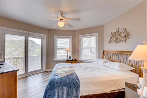 a bedroom with a bed with a ceiling fan and windows at Sea Esta 404 in Corolla