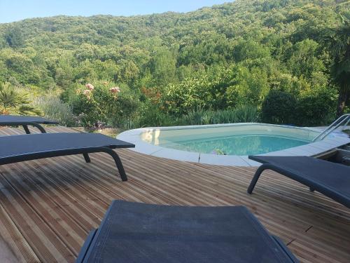a swimming pool on a wooden deck with two picnic tables at La Storya in Meyras