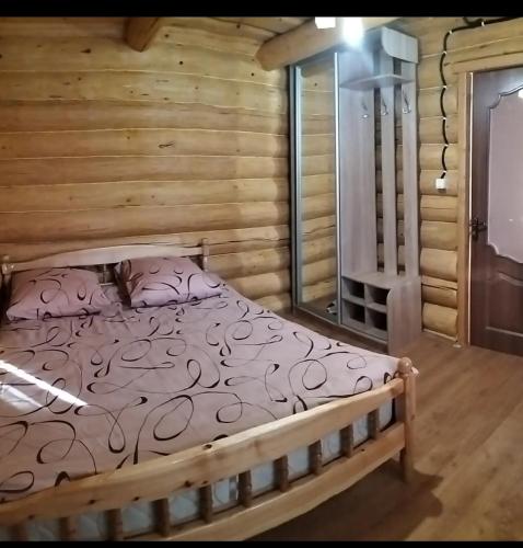 a bedroom with a bed in a log cabin at "Бджілка" і " Садиба для відпочинку" in Lyuta