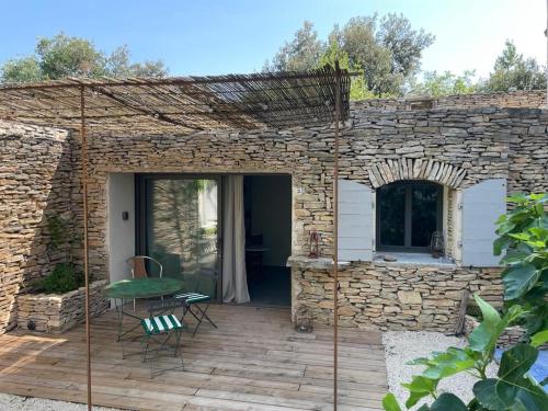 a patio with a stone wall and a table and chairs at La Finca in Nîmes