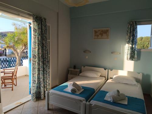two beds in a room with a balcony at ΑΥΡΑ Ενοικιαζόμενα Δωμάτια - AVRA Rooms To Let in Galissas