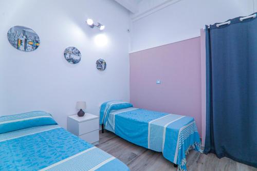two beds in a bedroom with blue and white at GIGLIO DI MARE Residence in Sellia Marina