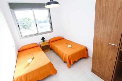 サロウにあるTramuntana Planet Costa Doradaのオレンジのシーツが備わる客室内のベッド2台