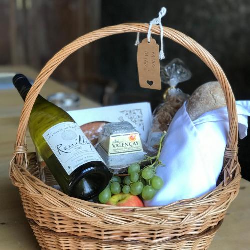 a basket with a bottle of wine and grapes at La Prairie Étoilée Luxury Glamping - Adults Only in Crozon-sur-Vauvre