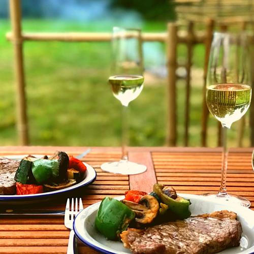a table with two plates of food and two glasses of wine at La Prairie Étoilée Luxury Glamping - Adults Only in Crozon-sur-Vauvre