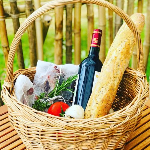 a basket with a bottle of wine and some food at La Prairie Étoilée Luxury Glamping - Adults Only in Crozon-sur-Vauvre