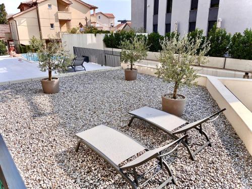 two chairs and potted trees on a patio at Fides Stylish Apartments Tivat with Pool in Tivat