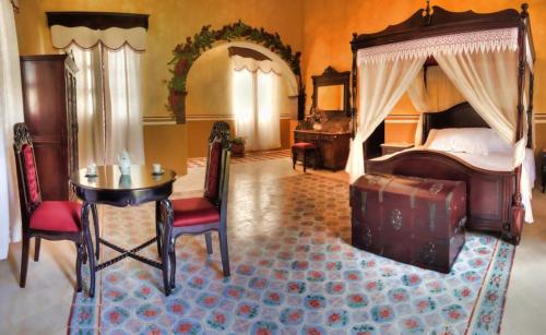 ein Schlafzimmer mit einem Himmelbett sowie einem Tisch und Stühlen in der Unterkunft Hacienda Kaan Ac in Valladolid