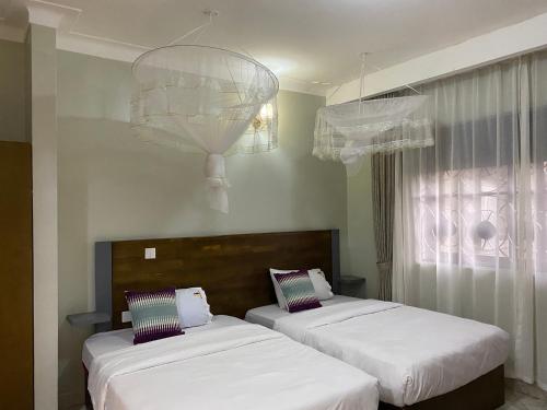 a room with two beds and a chandelier at Tenda Suites and Restaurant in Entebbe