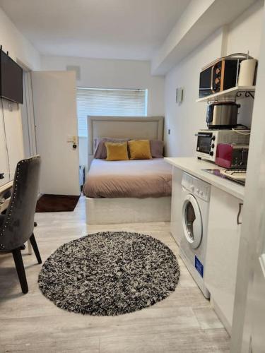 um quarto com uma cama e uma cozinha com uma máquina de lavar roupa em Studio Flat, close to o2 Arena and City Airport em Woolwich