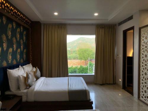 a bedroom with a bed and a large window at Bamboo Saa Mulberry Resort Pushkar in Pushkar