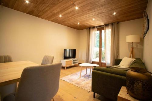 a living room with a couch and a table and a television at Appartement cosy Rez-de-jardin in Demi-Quartier