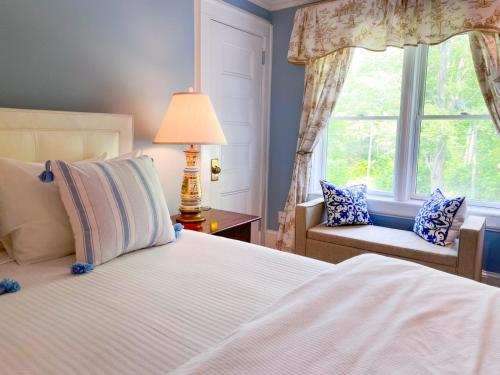 a bedroom with a bed and a chair and a window at Copper Beech Inn in Ivoryton