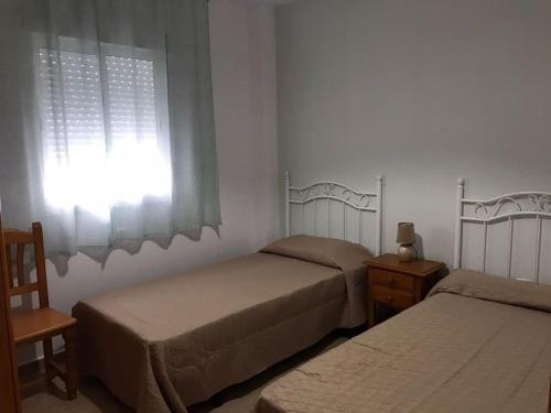 1 dormitorio con 2 camas individuales y ventana en Apartamento Conil, en Conil de la Frontera