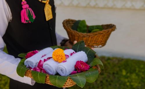 a person holding a basket of towels and flowers at The Rawla Narlai - A Luxury Heritage Stay in Leopard Country in Nārlāi