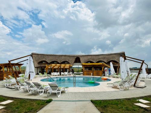 a swimming pool with lounge chairs and a pavilion at Complex Andris in Murighiol