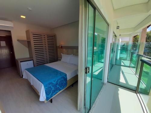 1 dormitorio con 1 cama y balcón de cristal en Ilhéus North Residence, en Uruçuca