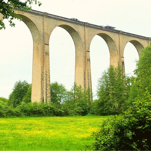 a bridge with a train on top of it at La Prairie Étoilée Luxury Glamping - Adults Only in Crozon-sur-Vauvre