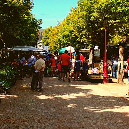 a group of people walking around a market with trees at La Prairie Étoilée Luxury Glamping - Adults Only in Crozon-sur-Vauvre