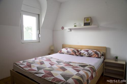 1 dormitorio con cama con edredón y ventana en Sunny 412 apartment en Podgorica