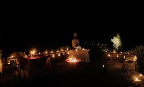 a man standing next to two tables at night at The Rawla Narlai - A Luxury Heritage Stay in Leopard Country in Nārlāi