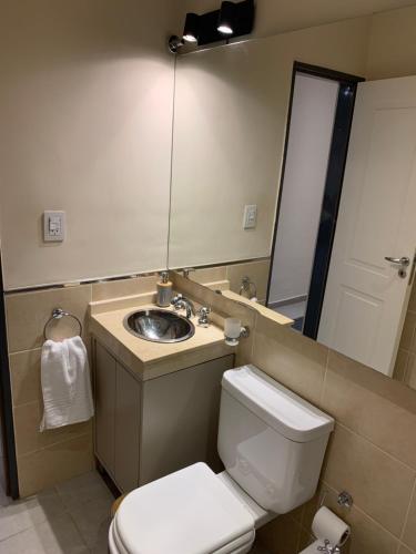 ein Badezimmer mit einem Waschbecken, einem WC und einem Spiegel in der Unterkunft Amaru - Departamento céntrico con cochera in Corrientes