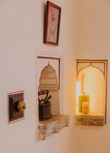 a room with a mirror and a candle on a wall at The Rawla Narlai - A Luxury Heritage Stay in Leopard Country in Nārlāi