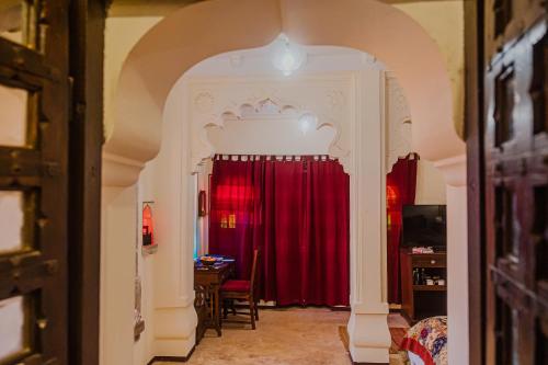 an archway leading into a room with a red curtain at The Rawla Narlai - A Luxury Heritage Stay in Leopard Country in Nārlāi