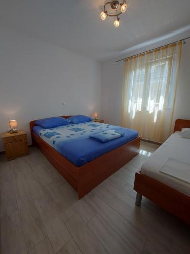 a bedroom with a bed with blue sheets and a window at Apartment Ante in Vlašići