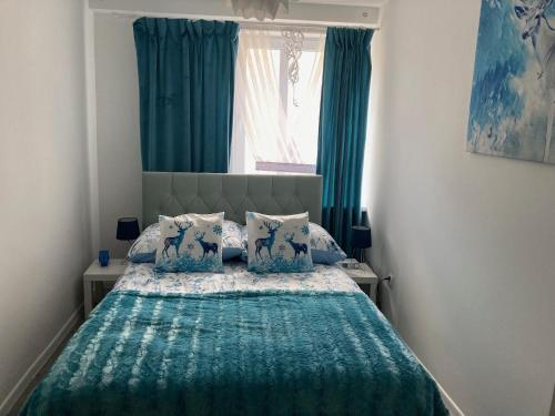 a bedroom with a bed with blue curtains and a window at Habibi Plac Ratuszowy in Jelenia Góra