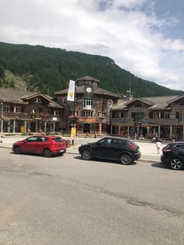 trois voitures garées sur un parking devant un immeuble dans l'établissement Charmant Studio, à Allos