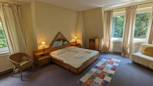 a bedroom with a bed and a chair and windows at Naturhotel Forsthaus in Annaberg-Buchholz