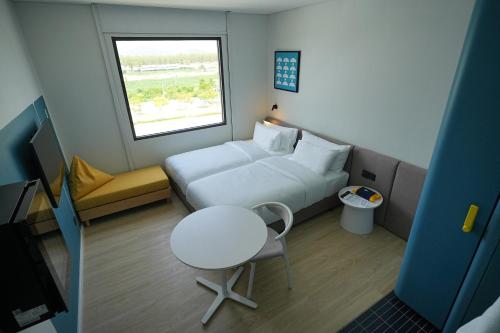 ein kleines Zimmer mit einem Bett, einem Tisch und einem Fenster in der Unterkunft GO! Hotel Ban Chang at Robinson Lifestyle Ban Chang in Ban Chang