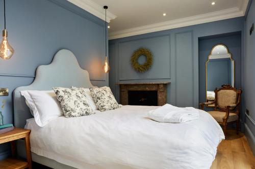a bedroom with a white bed with blue walls and a fireplace at Railway House York by Chateau Anna in York