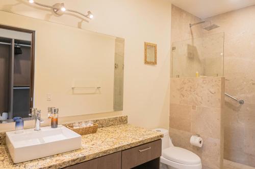 ein Badezimmer mit einem Waschbecken, einem WC und einem Spiegel in der Unterkunft Nayri Life & Spa 408 in Puerto Vallarta