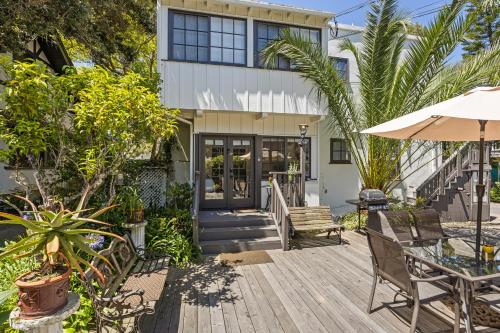 a house with a wooden deck with chairs and an umbrella at East Beach Retreats in Santa Barbara