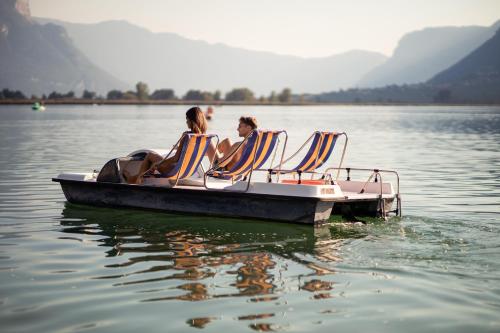 two people sitting in chairs on a boat on the water at Parc Hotel Am See in Caldaro