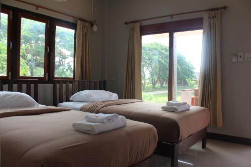 two beds in a room with two windows at Resort Railumpoo (Farm and Camping) in Nakhon Sawan