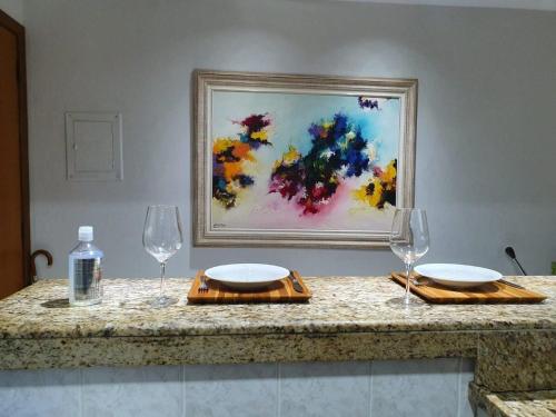 una mesa con dos vasos y una pintura en la pared en Recanto Maravista apto Frente Mar 2 quartos, en Vila Velha