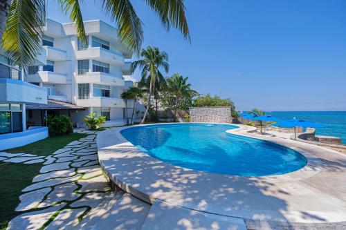 a swimming pool in front of a building next to the ocean at Suites Turquesa in Cozumel